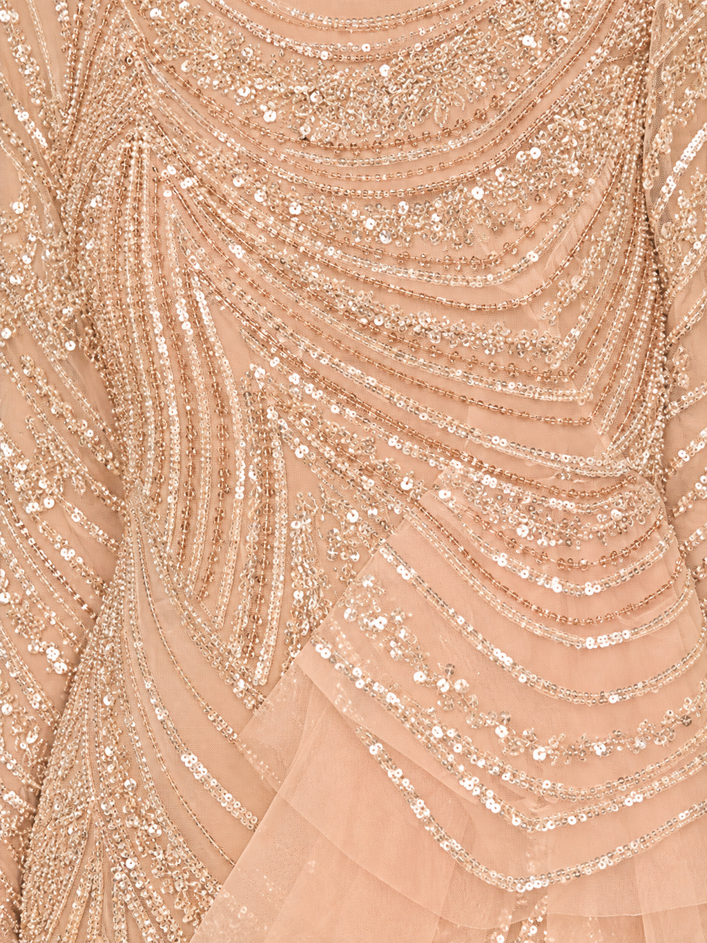Close-up of a peach-beige embellished fabric with layered sequins and beadwork arranged in flowing curved lines.