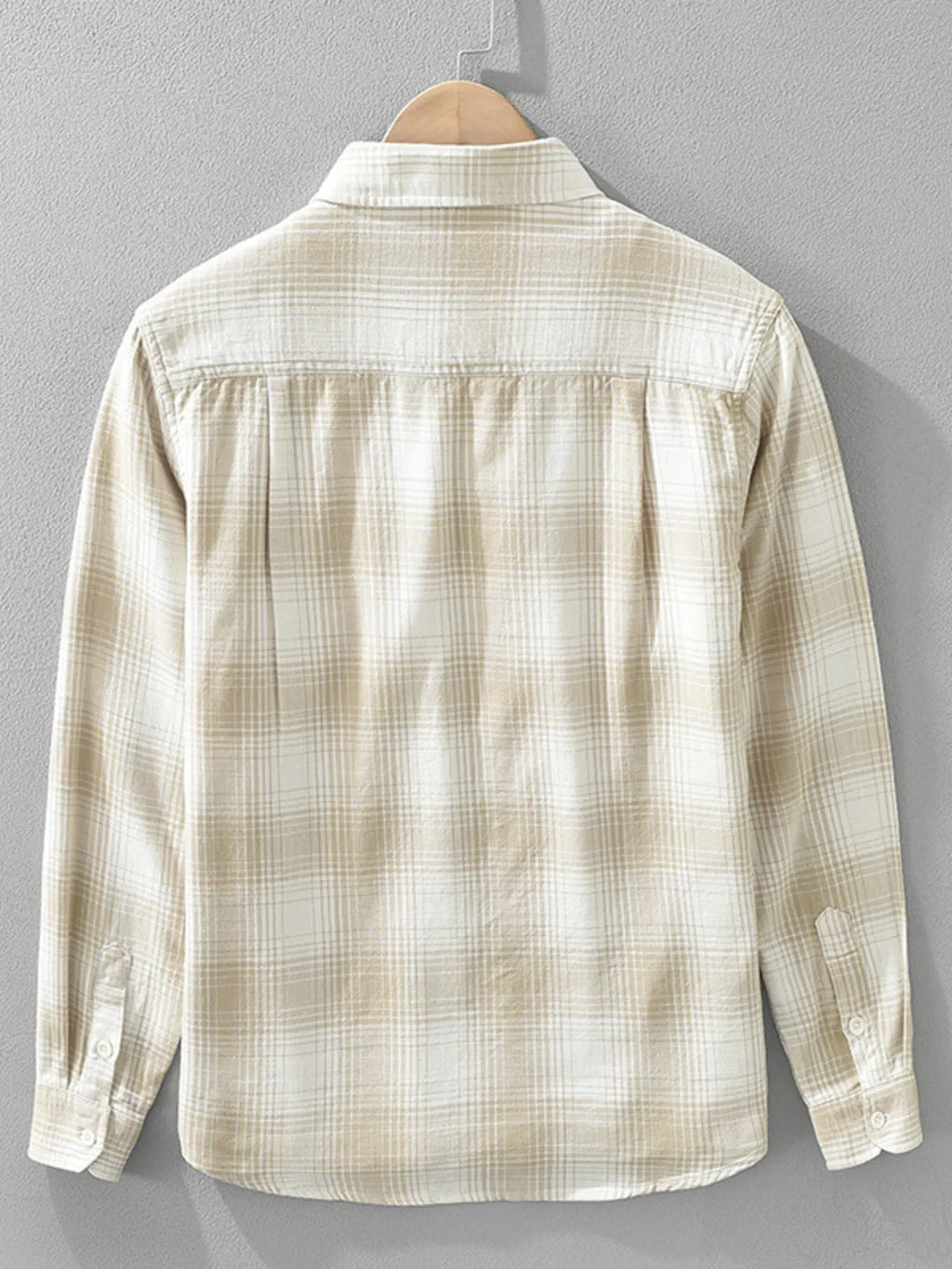 Beige plaid shirt on a hanger against a gray background
