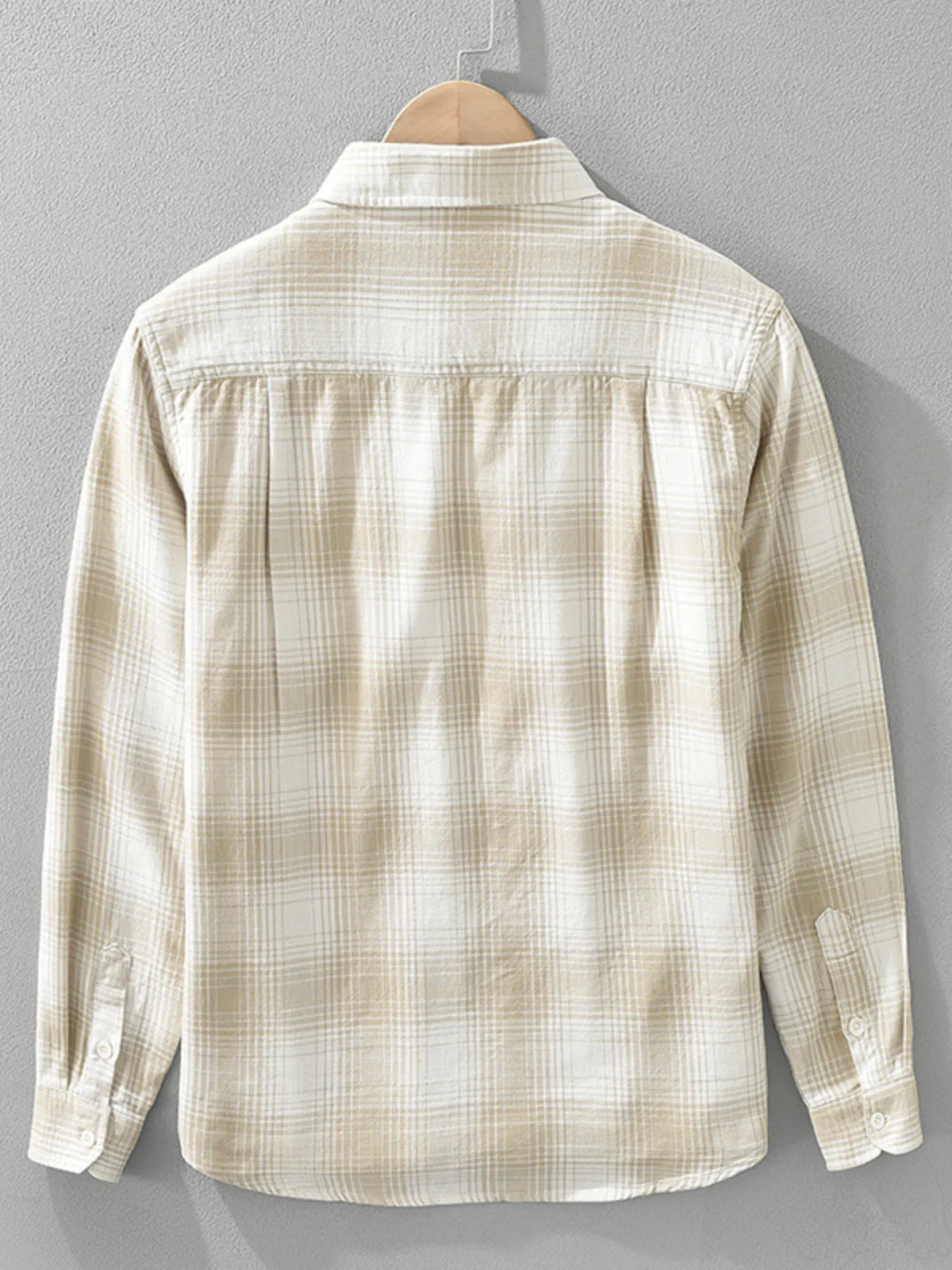 Beige plaid shirt on a hanger against a gray background